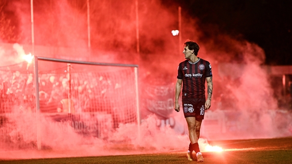 Dylan Connolly of Bohemians walks away from flares thrown onto the pitch at Richmond Park