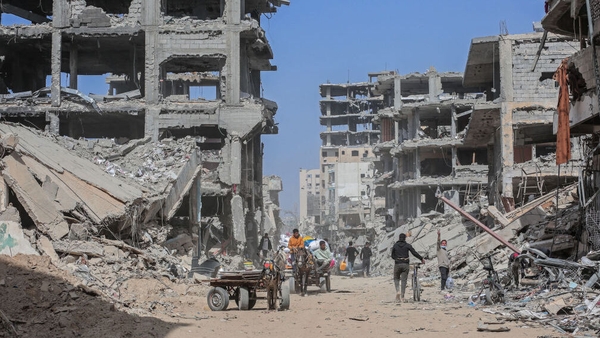 Displaced Palestinians transport their belongings by horse cart amid the rubble of destroyed homes in Khan Younis