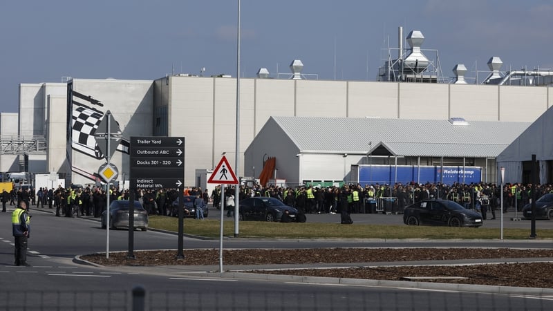 Employees gather ahead the arrival of Tesla CEO Elon Musk at the company's electric car plant in Gruenheide, Germany