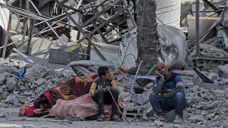 Displaced Palestinians sit with their belongings amid the rubble of houses destroyed by Israeli bombardment in Hamad area, west of Khan Younis