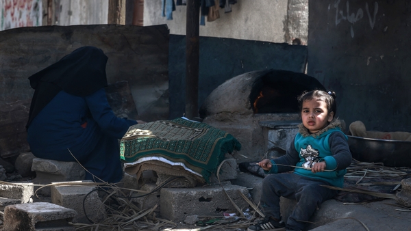 A girl sits next to a woman making bread at the Rafah refugee camp in southern Gaza