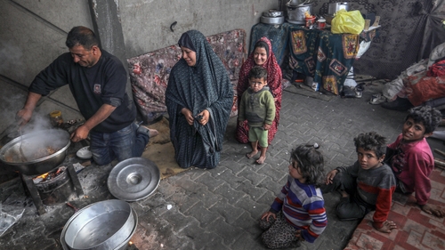 Mná agus leanaí Palaistíneacha ag breathnú go hairceach ar an mbéile caol, Rafah, Gaza, 28 Márta 2024