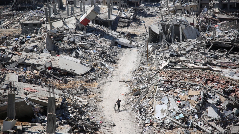 A man pushes a bicycle along as he walks amid building rubble in the devastated area around Gaza's Al-Shifa hospital