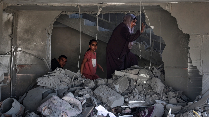 A Palestinian woman and children check the rubble of a building hit by overnight Israeli bombing in Rafah