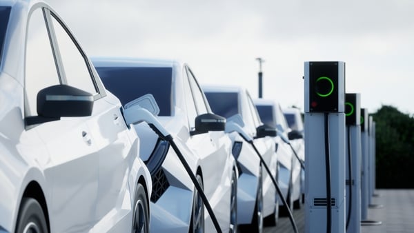a row of white electric cars plugged into charging stations