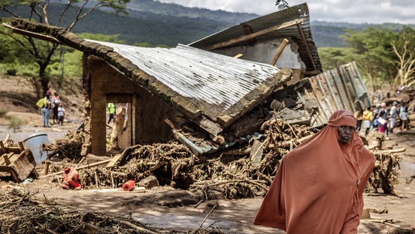 A woman walks past destroyed houses covered in mud and debris carried by floodwaters in central Kenya