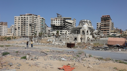 Palestinians walk past damaged and destroyed buildings in Gaza city in the north of the enclave