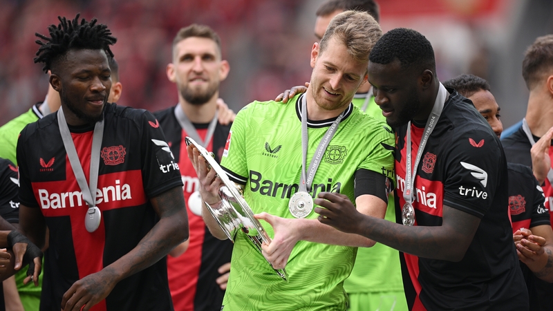 Lukas Hradecky (L) and Victor Boniface celebrate with the Meisterschale of Bundesliga trophy
