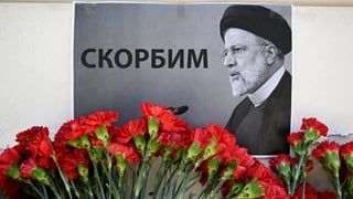 People bring flowers to the Iranian embassy to pay tribute to Iran's President Ebrahim Raisi