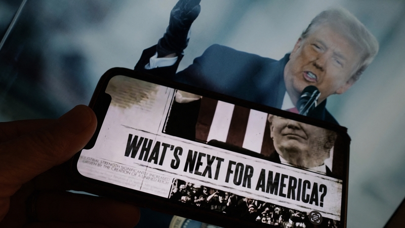 An illustration created by AFP shows a frame from a video posted on Donald Trump's Truth Social account displayed on a smartphone in front of a photo of the former US president