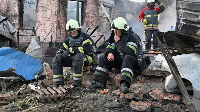 Firefighters rest after extinguishing a fire in a house destroyed by a Russian drone attack in of Kharkiv
