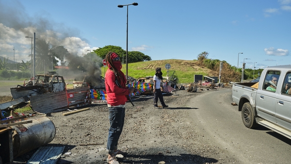 People man a roadblock barricade, with Kanak flags, controlling access to a district in Noumea