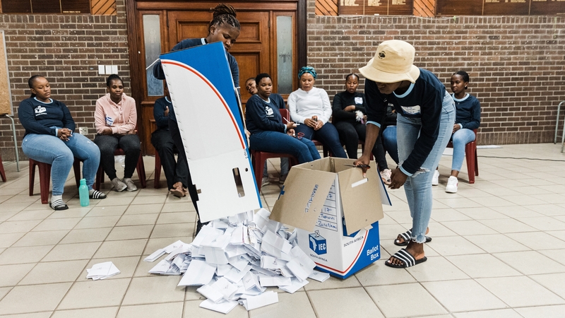 Officials from South Africa's Electoral Commission empty a ballot box as the vote counting process gets under way