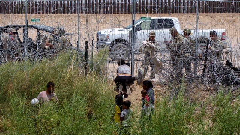 Some migrants await the opportunity to cross the border while Texas National Guard and state police prevent crossings