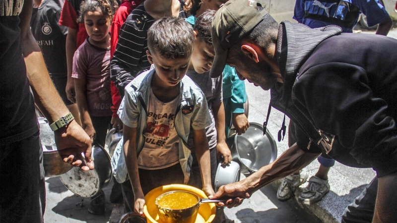 Palestinian children line up as food is distributed in a Jabalia camp in Gaza