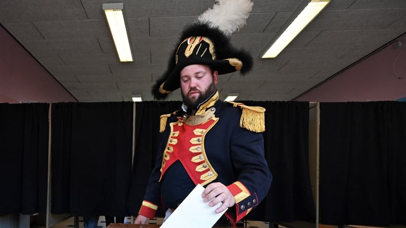 A man, who was taking part in a traditional parade, voting in Belgium yesterday