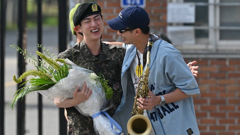 BTS member Jin (left) is greeted by fellow BTS member RM after being discharged from his mandatory military service outside a military base in Yeoncheon, South Korea