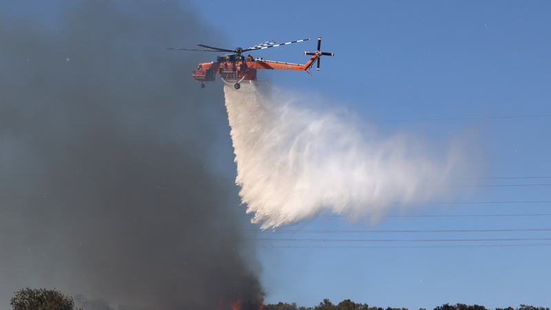 A firefighting helicopter makes a water drop during a wildfire, in Kitsi, near the town of Koropi