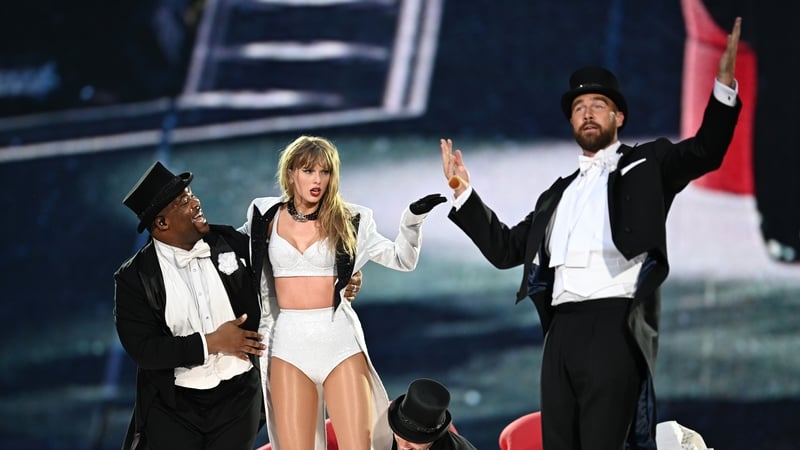 Taylor Swift pictured with Travis Kelce on stage (r)