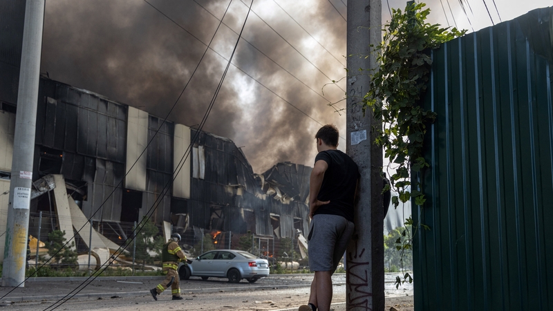 A man watches on as Ukrainian firefighters work to extinguish a blaze caused by a Russian strike on Odesa