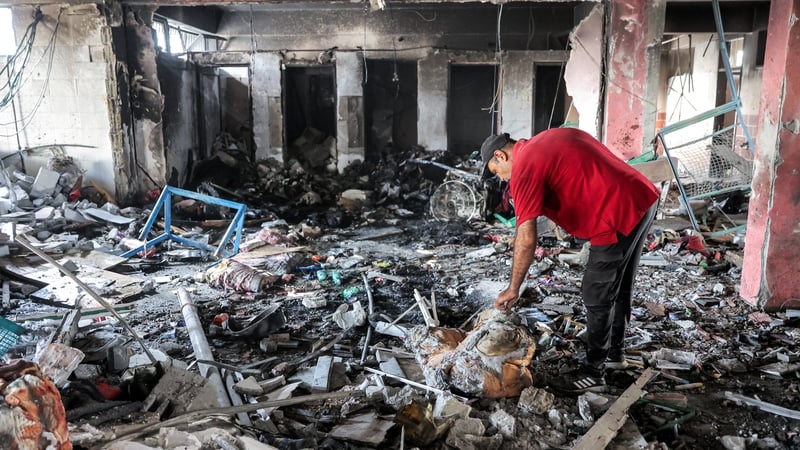 A man searches through charred debris in a room at Asma school in the Shati refugee camp west of Gaza City