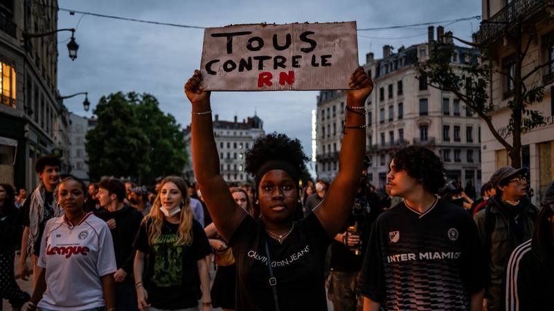 A protester holds a sign at a demonstration which says 'all against the National Rally' in French