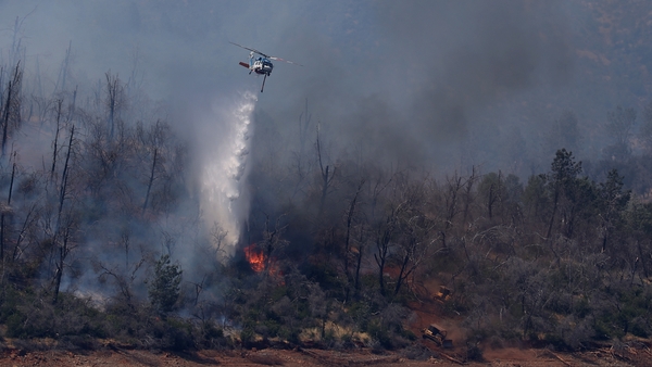 A firefighting helicopter drops water on a wildfire in Oroville, California