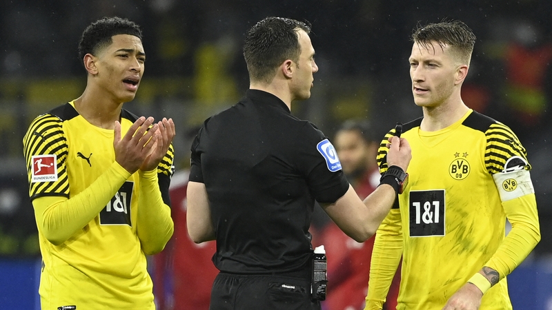 Jude Bellingham (L) and Marco Reus (R) talk to referee Felix Zwayer during the Borussia Dortmund v Bayern Munich game in 2021