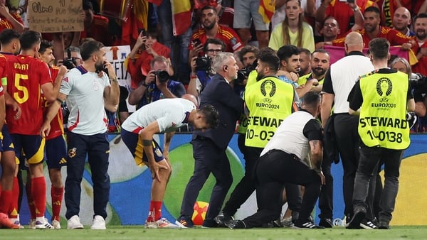 Alvaro Morata holds his leg after a member of security collided with the Spanish striker while attempting to remove a pitch invader after the full-time whistle