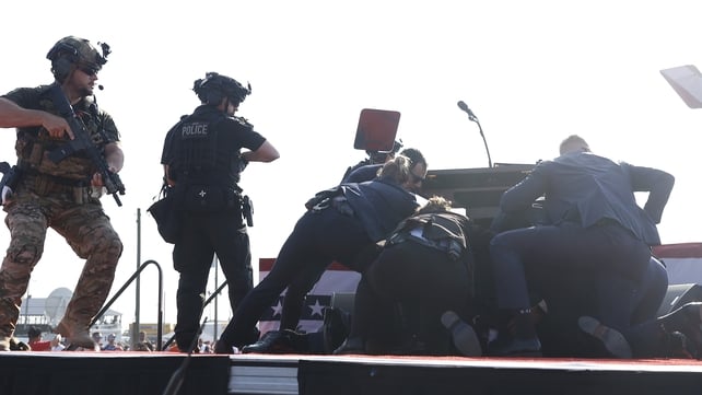 Secret Service agents protect Mr Trump on the podium after he was shot