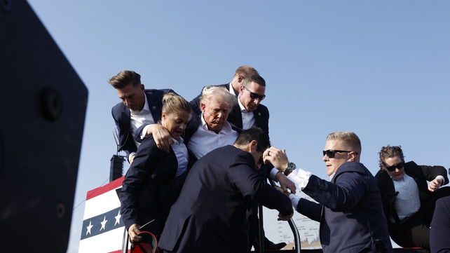 Donald Trump is rushed from the podium after he was shot in the ear