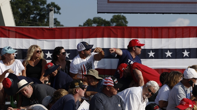 People at the rally react as the sound of gun shots were heard as Mr Trump addressed the crowd