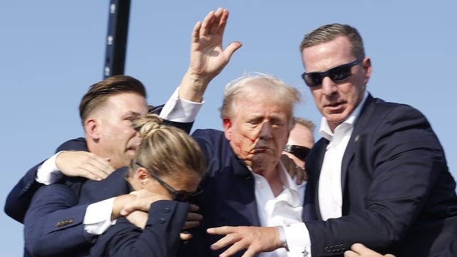 The former president raised his arm in defiance as he was led off the stage