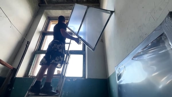 A worker installs a polyethylene window in an apartment block in eastern Ukraine