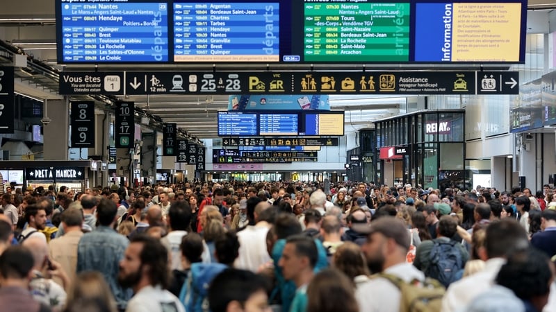 Passengers gather around departure boards at Gare Montparnasse train station in Paris as France's high-speed rail network was hit by 'malicious acts'