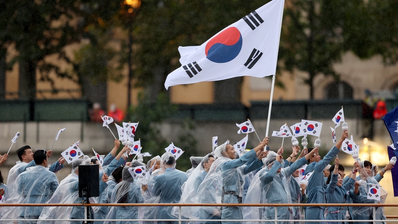 Seoyeong Kim and Sanghyeok Woo, Flagbearers of Team Republic of Korea, are seen waving their flag along the River Seine during the opening ceremony