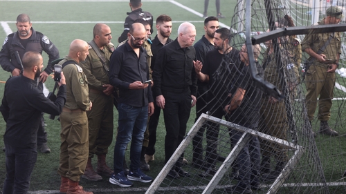Israeli Minister of Defence Yoav Gallant (C) visits the site of the strike