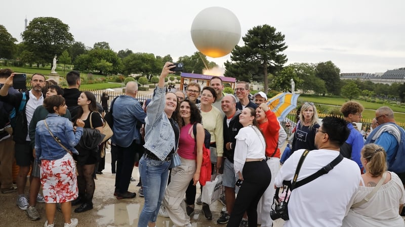 People take selfies in front of the Olympic cauldron installed in the Tuileries Garden in Paris