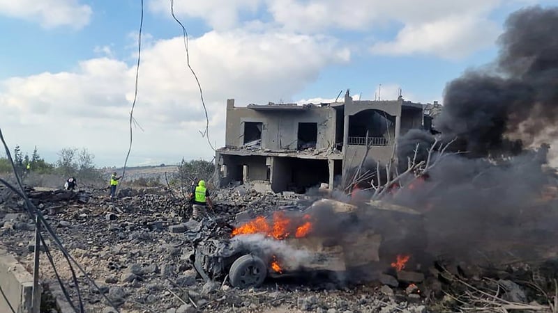 Lebanese civil defence workers search the scene as vehicles burn following an Israeli air raid on the town of Shamaa in southern Lebanon on Thursday