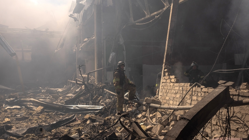 Rescue personnel stand in debris after a Russian artillery strike on a supermarket in the east Ukrainian town of Kostyantynivka killed at least ten people