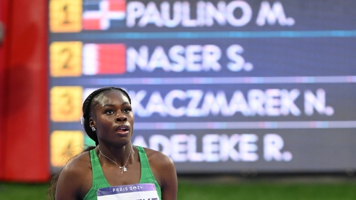 Adeleke walks past the timing screen showing the top four finishes in the 400m final