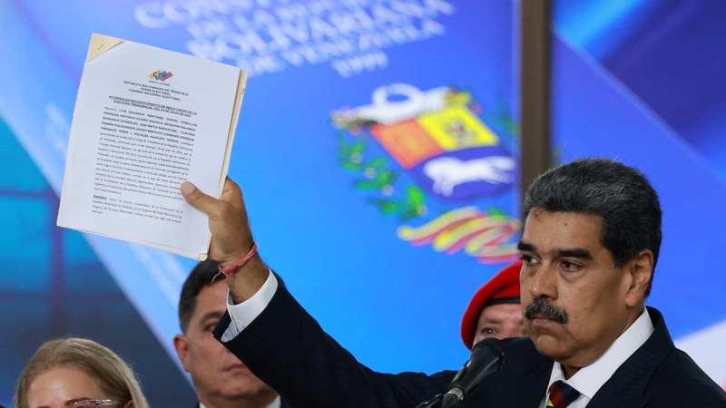 Nicolas Maduro shows a document while speaking to the press after appearing before the electoral chamber of the Supreme Court
