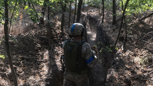 Ukrainian soldiers of the 'Da Vinci Wolves' battalion walk through a trench towards their mortar position in the direction of Pokrovsk on 31 July