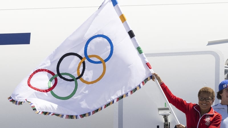 Los Angeles Mayor Karen Bass stepped off the plane dressed in a red Team USA tracksuit and waved the Olympic flag