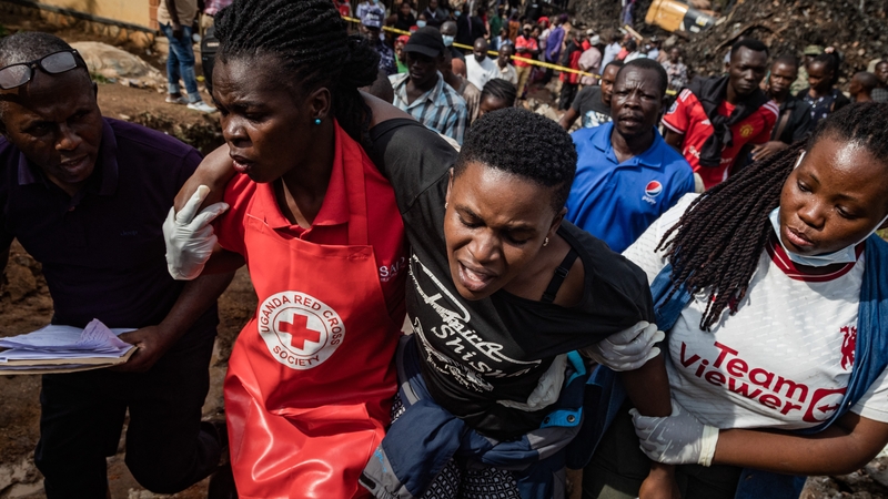Red Cross workers support a woman whose daughter and brother died when their house was hit by the collapsing Kiteezi landfill in Kampala