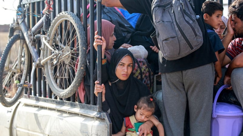 Palestinians displaced by the war travel in the back of a truck
