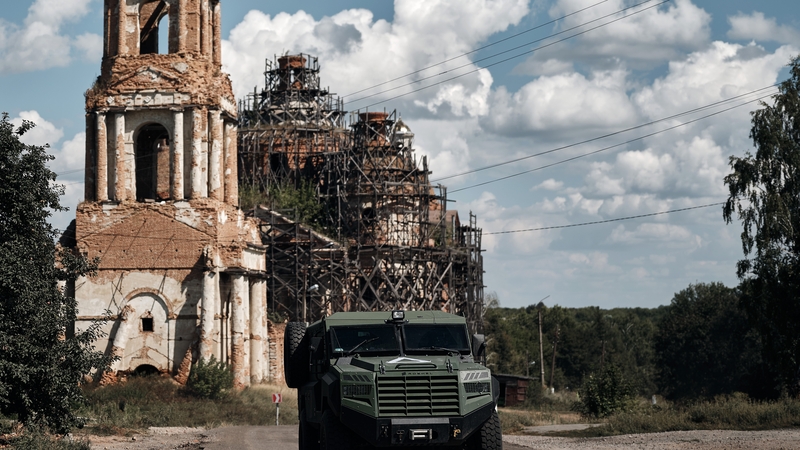 A Ukrainian armoured infantry vehicle travels past an unfinished church on the road from Sumy to the border with Russia