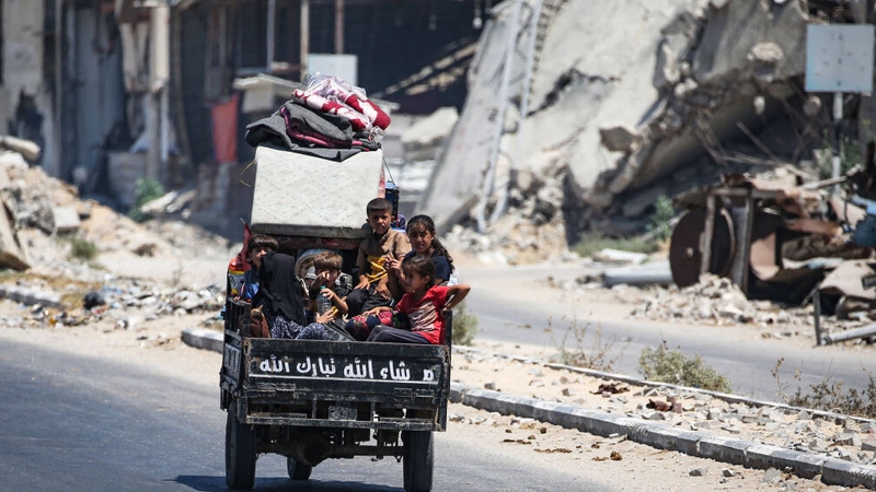 Children sit in the back of a small vehicle as Palestinians flee with their belongings Deir el-Balah