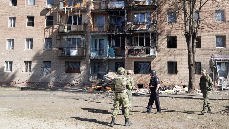 Local volunteers walk past a building damaged by Ukrainian strikes in Kursk yesterday