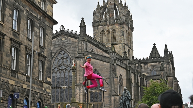 A street performer goes through her act above the crowds thronging the Royal Mile, against a backdrop of St Giles' Cathedral, during the Edinburgh Festival Fringe. (Photo by Ken Jack/Getty Images)